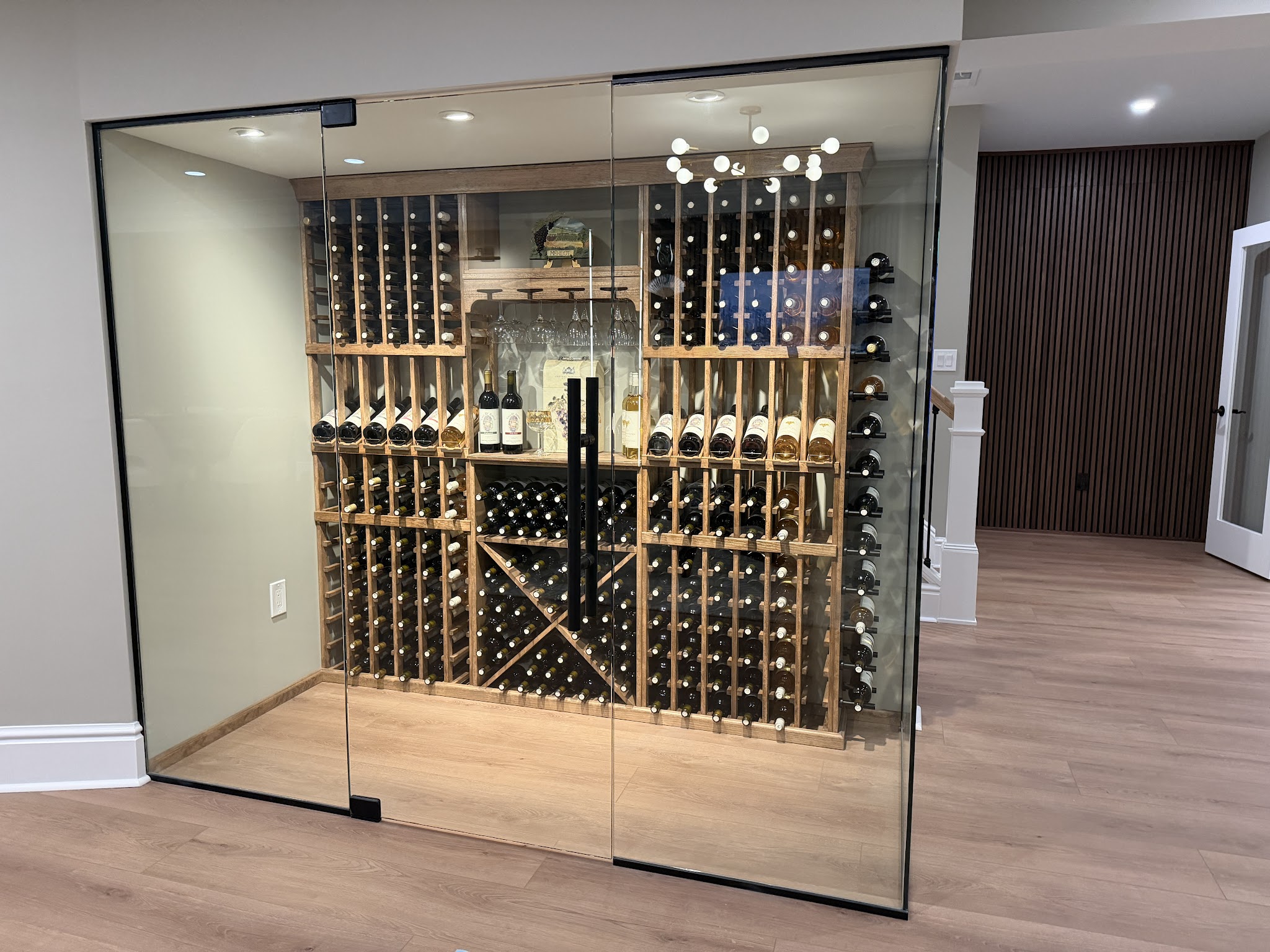 Glass Wine Room — A glass-enclosed wine room with custom racking — a centerpiece of the basement.