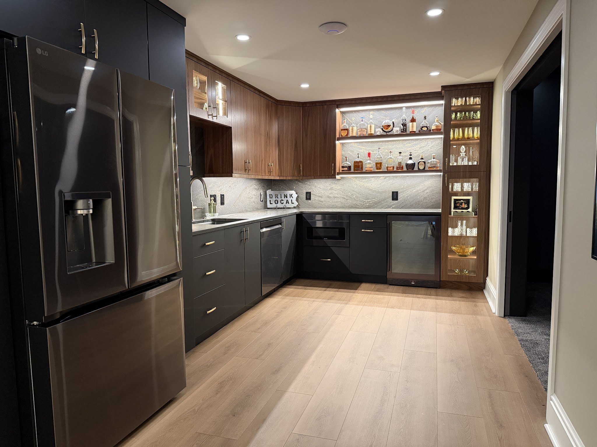Basement Wet Bar & Kitchenette — A full kitchenette and wet bar with floating shelves and a tile backsplash.