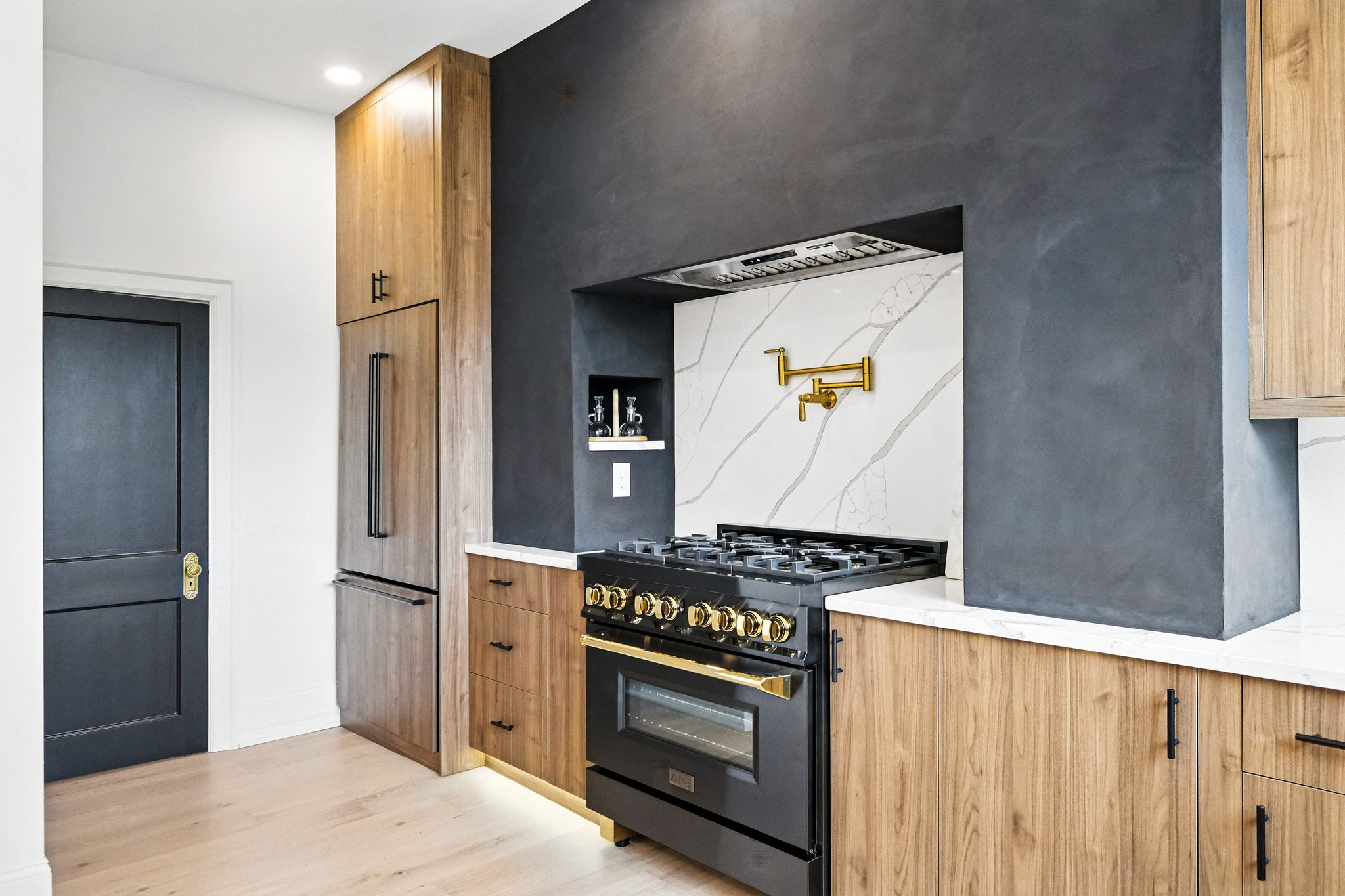 A finished modern kitchen by Pittsburgh Property Remodelers — wood cabinetry, quartz counters, and a brass pot filler
